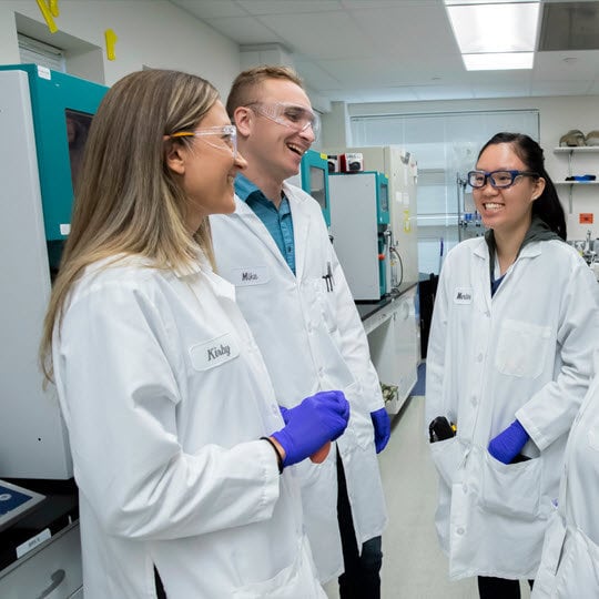 Four lab-coated professionals share ideas, emphasizing Teva's commitment to improving health daily.