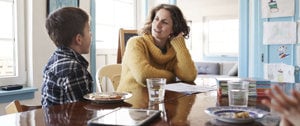 A woman and two children sit at a table, reflecting on family life with a chronically ill parent.