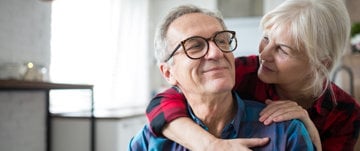 Senior man being hugged and comforted by his wife as he deals with worries about heart failure.