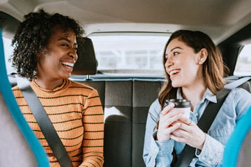 A caregiver and her friend sit in the car, getting ready to visit the doctor.