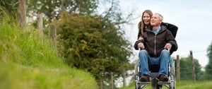 Caregiver and loved one in wheelchair happily living in the moment as they go for a walk