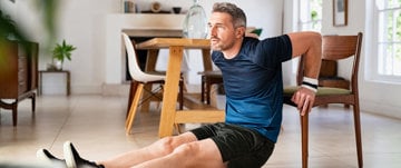 Male caregiver performing chair exercises in his kitchen to stay healthy 