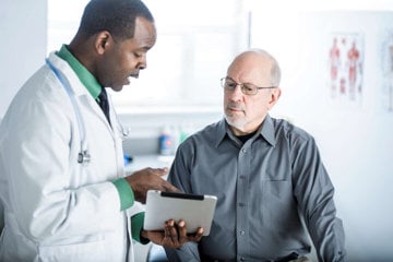 Male caregiver discussing with with his doctor how to get treat his loved one's health with excellent communication