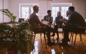 A group of young adults sitting in a room and sharing their mental health stories and experiences.