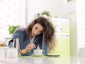 Woman dealing with brain fog stares blearily into a mug of coffee