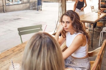 Woman getting bored in coffee shop as her friend dominates the conversation with over-explaining 