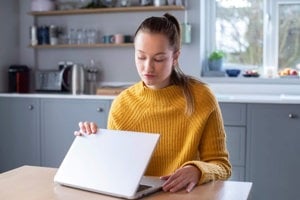 Woman concerned about triggering cancer awareness month content on social media closing lid of laptop computer