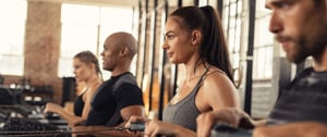 Woman with asthma enjoying cardio workout class on rowing machine