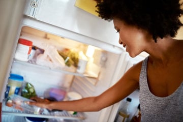 Woman with asthma searches the contents of her fridge for something healthy to eat.