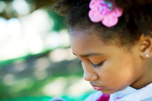 Young girl looking down guiltily as she struggles with ADHD and low self-esteem