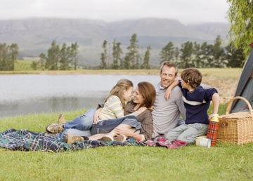 Happy family having picnic by the river, enjoying the weekend, despite migraine