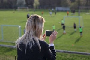 Mom with chronic migraine taking photos of her children playing soccer after school 