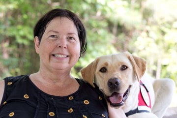 huntingtons-disease-patient-sarah-foster-with-her-service-dog-rupee-a-smiling-yellow-labrador-retriever