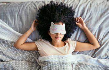 woman in bed with cover over face