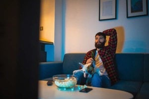 Young man watching TV shows with his dog shocked at inaccuracy of depression portrayal onscreen