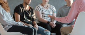 A group of individuals engaged in conversation while seated, exploring themes of learning from depression.