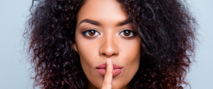 A woman with her finger on her lips, conveying a message of quiet reflection regarding ADHD and communication challenges.