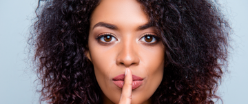 A woman with her finger on her lips, conveying a message of quiet reflection regarding ADHD and communication challenges.